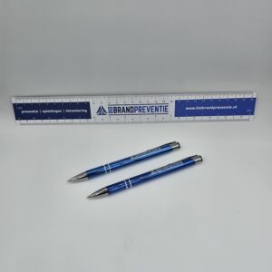Een blauwe schaal liniaal van BIO Brandpreventie, gepresenteerd samen met een bijpassende pen en potlood, beide bedrukt met het logo van BIO Brandpreventie.